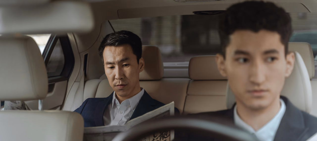 Chauffeur driving an executive passenger seated in the rear of a luxury car