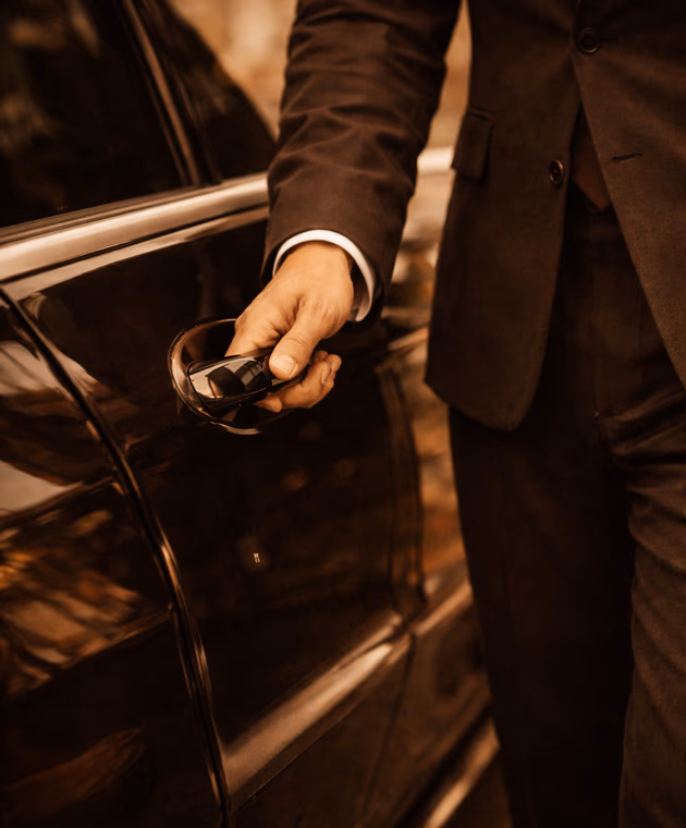 Chauffeur opening the door of a black executive car
