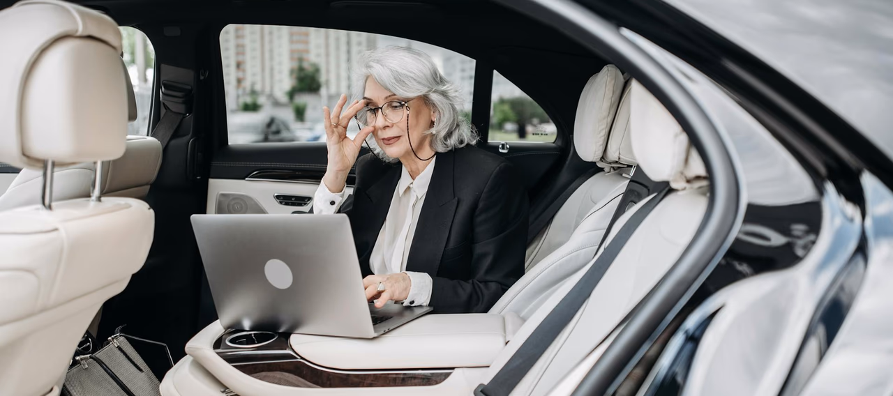 Executive working on a laptop in the back of a luxury chauffeur-driven car
